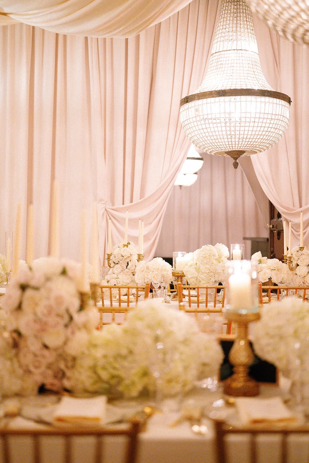 A tented dinner with white drapes, white flowers and candles