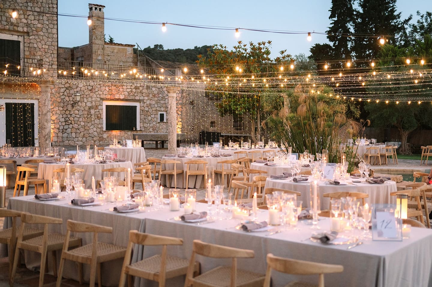 Long dinner tables under strings of lights in the courtyard of a Mallorcan finca