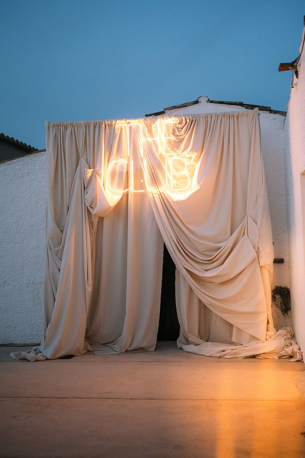 A neon sign glowing between draped ivory fabric
