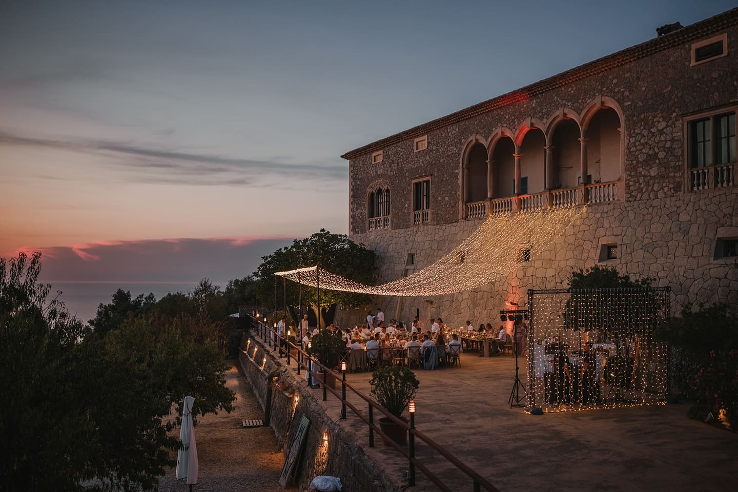 Guests gathering on the terrace of a stone finca at sunset before dinner