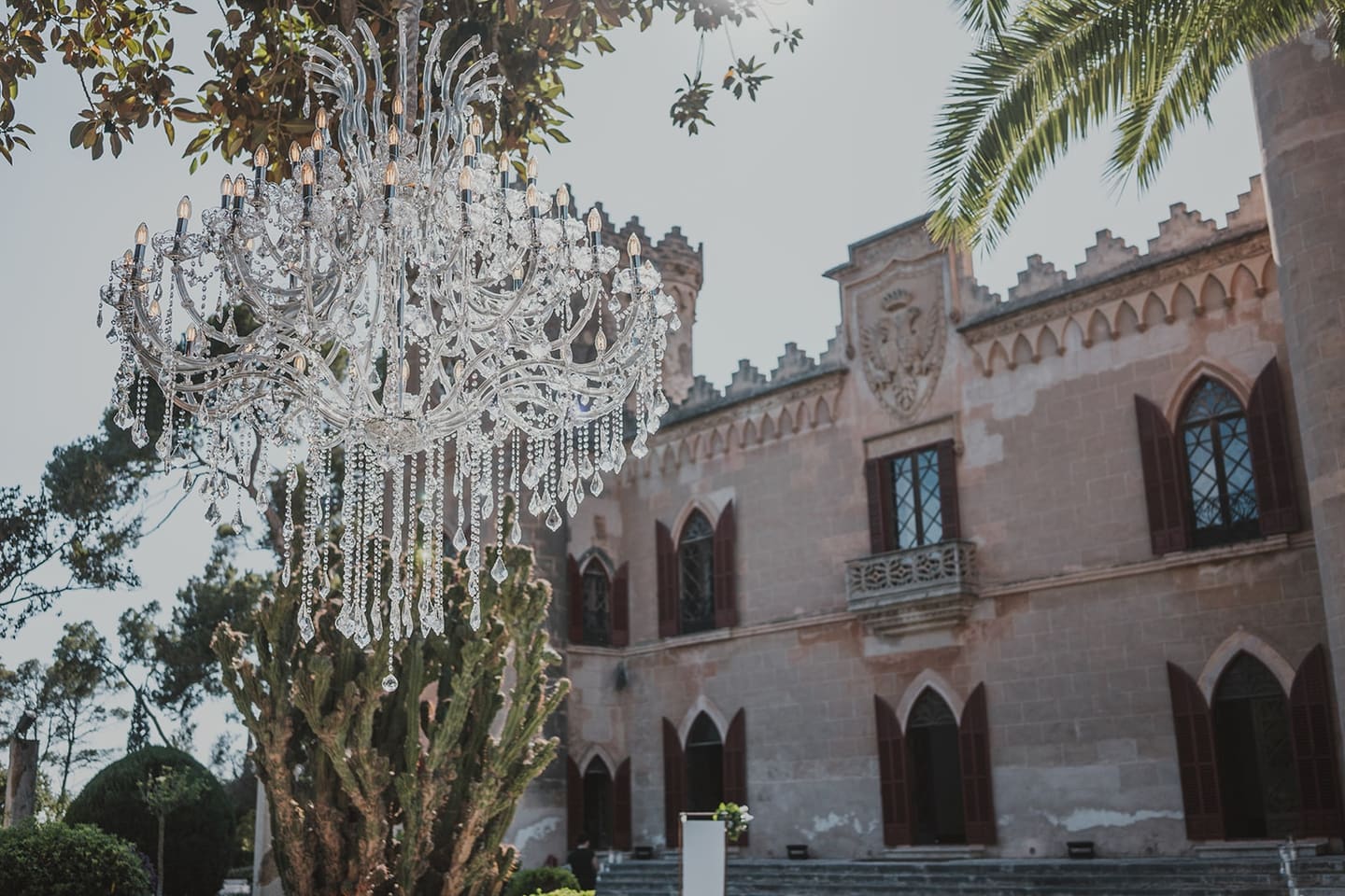 A crystal chandelier hung from a tree in front of a Mallorcan palace