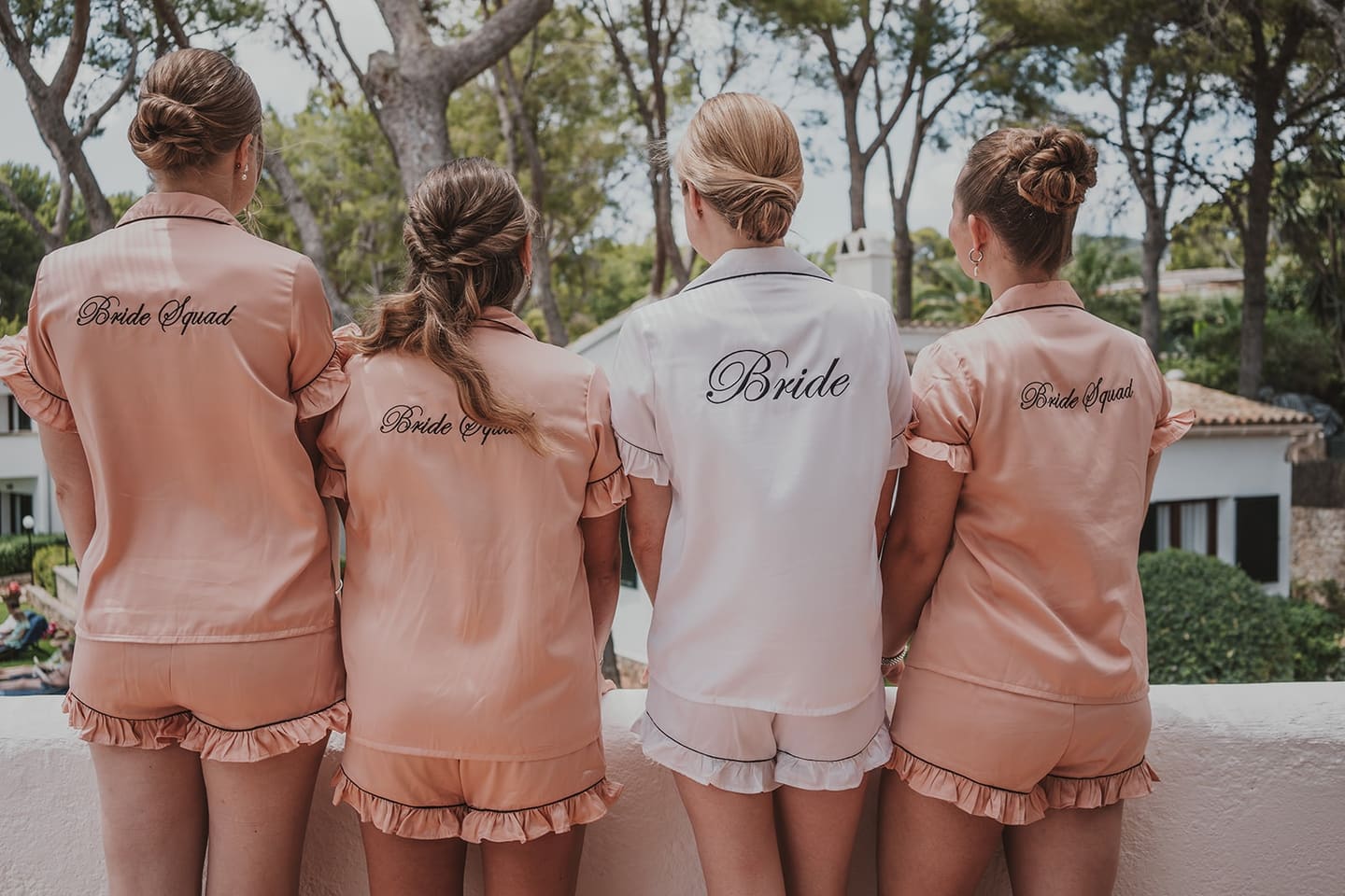 Bridesmaids in peach robes seen from behind on the morning of the wedding