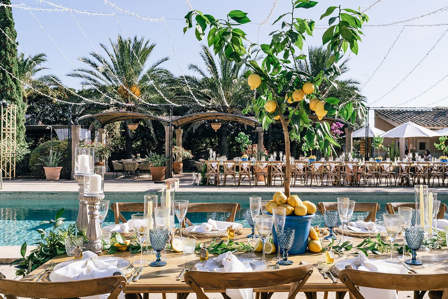A poolside wedding table beneath a lemon tree with blue glassware