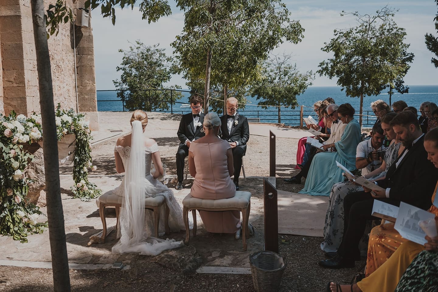 A couple exchanging vows in an outdoor ceremony on a stone terrace above the sea in Mallorca